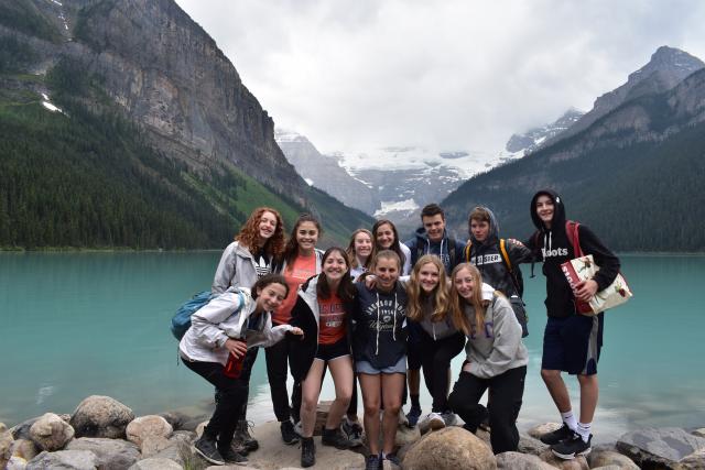 Teens posing in front of a lake and mountains on a summer tour of Canada