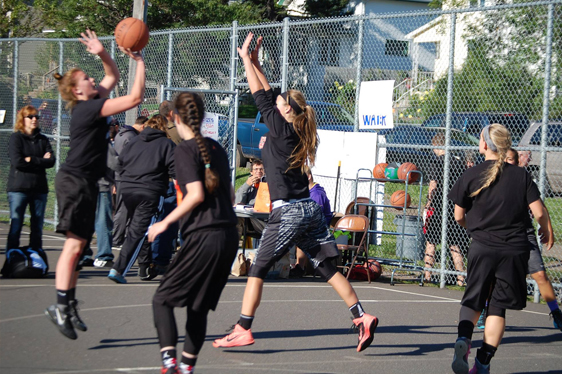 Girls rookie basketball team playing a game on an outdoor court