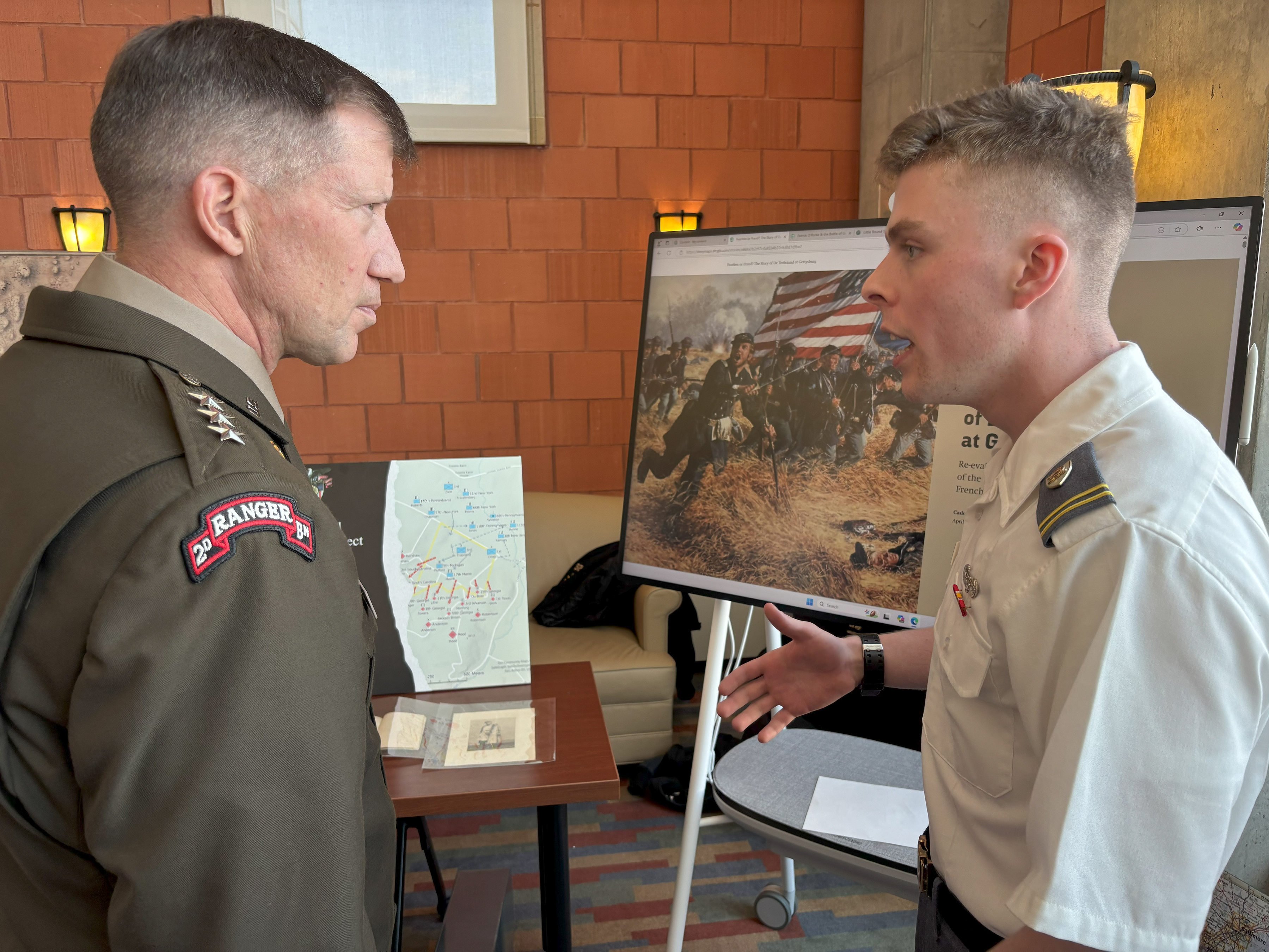 A Cadet working with West Point's Digital History Center briefs LTG David M. Hodne, Director, Futures and Concepts Center: Army Futures Command, on how the digital terrain mapping of the "Global Gettysburg." Project can support modern warfighting and greater tactical understanding at the 2025 Projects Day Research Symposium in April 2025. (Photo Credit: Courtesy Photo)