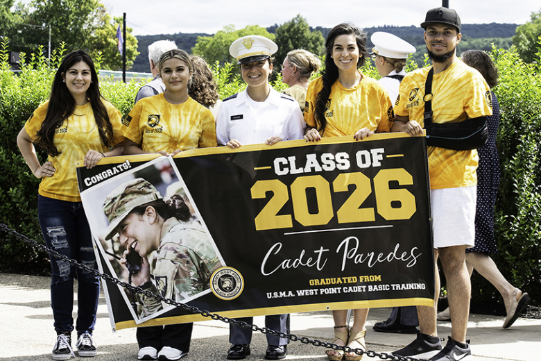 Class of 2026 Cadet Mirtha Paredes holds a banner with family members congratulating her on making it through Cadet Basic Training. 	 (Photo by Elizabeth Woodruff/USMA PAO)