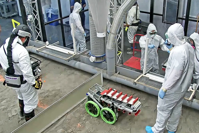 Class of 2023 Cadet Patrick McGurrin and Class of 2024 Cadet Ryan Logan set up the robot with NASA judges in the luna simulation arena. 							        Photo via NASA livestream CCTV, YouTube