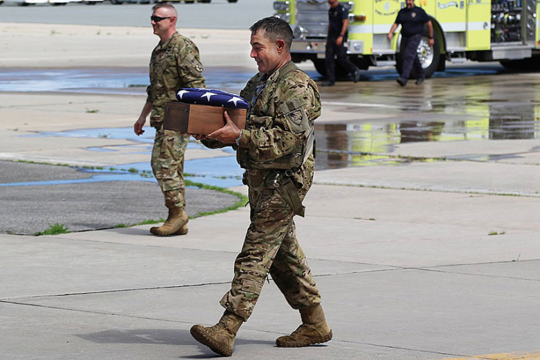 CW5 Joseph Roland proudly walks toward the hangar cradling an American flag and  a beautiful wooden box containing his father’s remains. Photo by Capt. David Hoy/USMA PAO