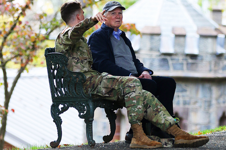 A cadet points out something to his grandfather as they sit on a bench at Trophy Point. 