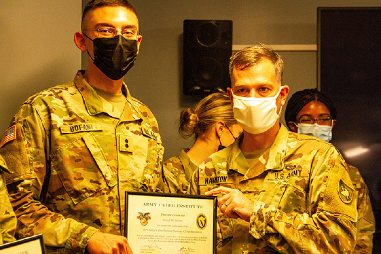 Reserve Officersʼ Training Corps Class of 2022 Cadet Joseph Bofani (left) receives a certificate from Col. Stephen Hamilton (right), an assistant professor at the Department of Electrical Engineering and Computer Science, after completing an eight-week summer internship program designed to provide real-world futuristic cyber research experience to ROTC cadets on Aug. 30 at the Army Cyber Research Institute.