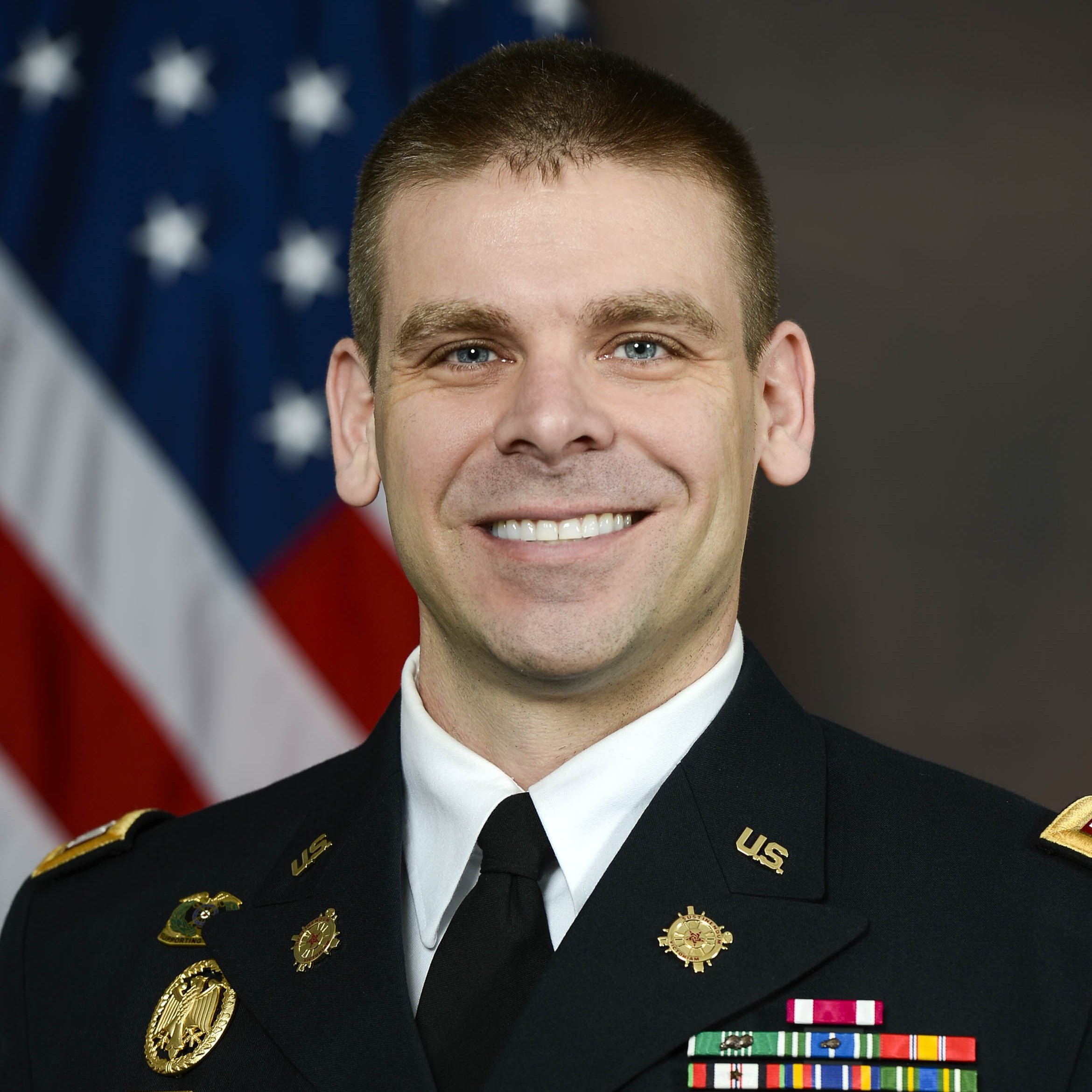 Portrait of MAJ Prokos in front of an American flag.
