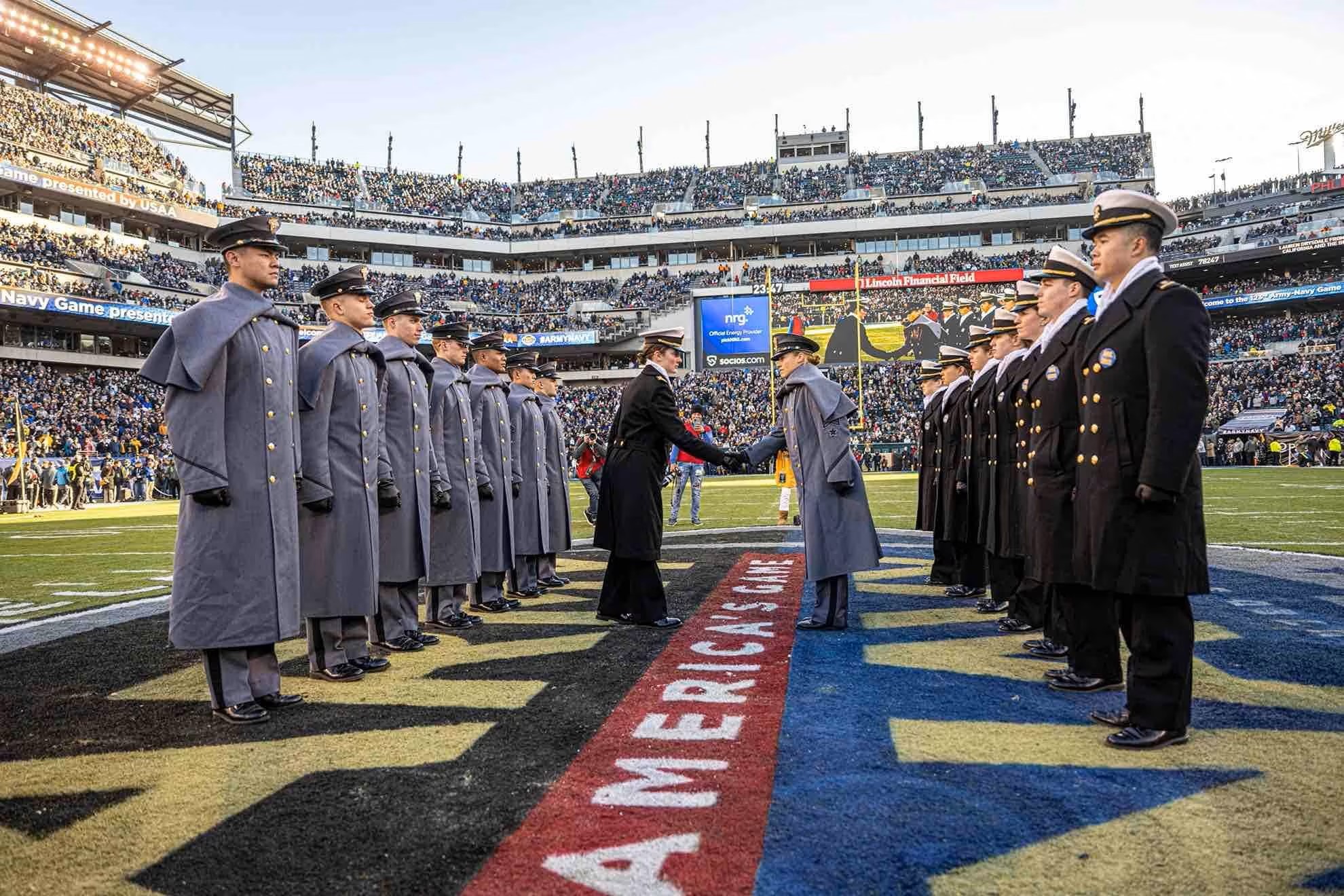 Students shake hands at the 50 yeard line at the Army Navy Game