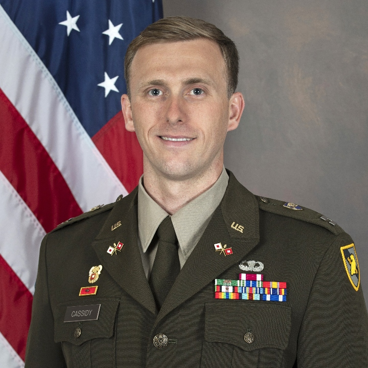 CPT Kenneth Cassidy in AGSU in front of American flag.