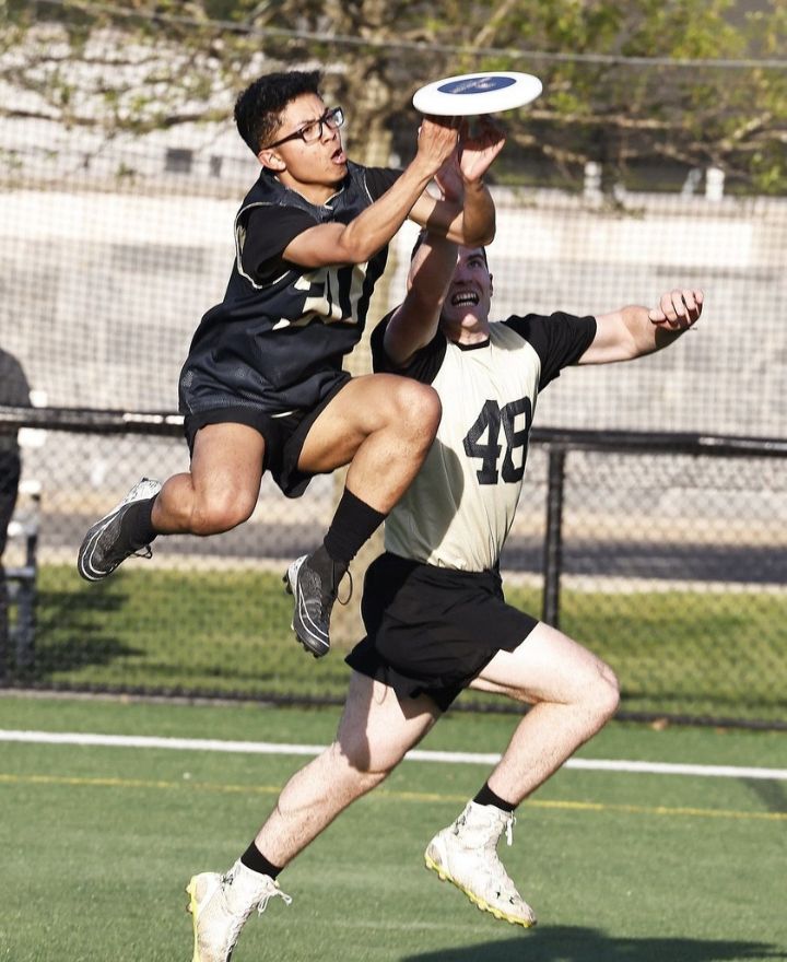 Cadet jumping over another to catch a frisbee