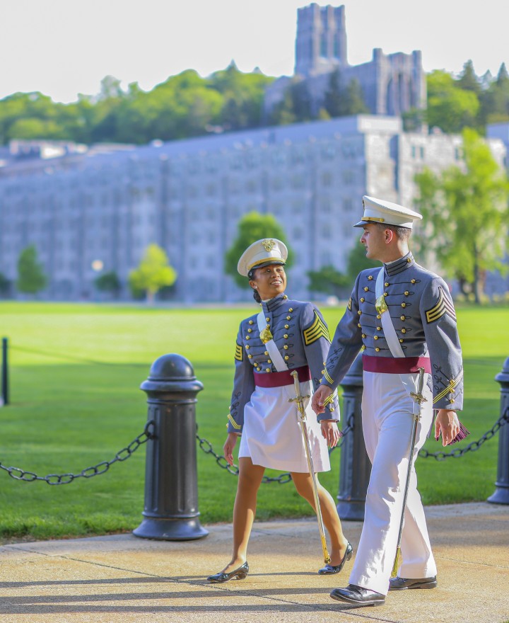 Two cadets in full dress stroll past the Plain.