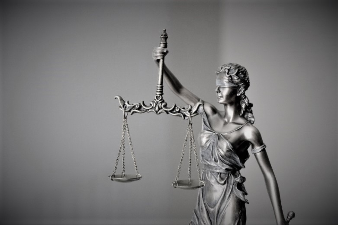 A statue of Lady Justice wearing a blindfold holds balanced scales aloft, symbolizing fairness and the legal system.