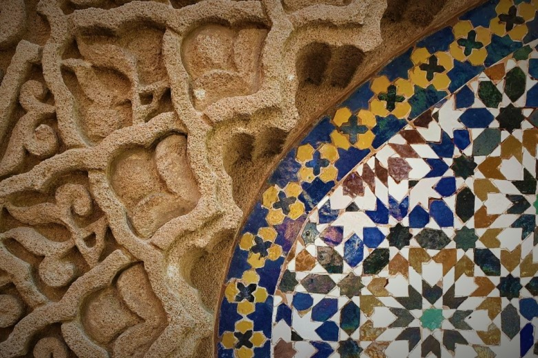Close-up of an ornate architectural design featuring intricate carved stone patterns beside a colorful geometric mosaic tile arrangement.
