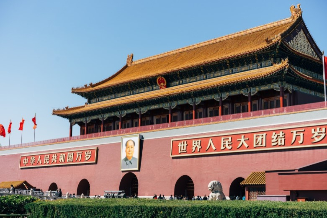 Wide view of a large traditional Chinese building with ornate golden roof architecture and red walls, located in Tiananmen Square in Beijing.