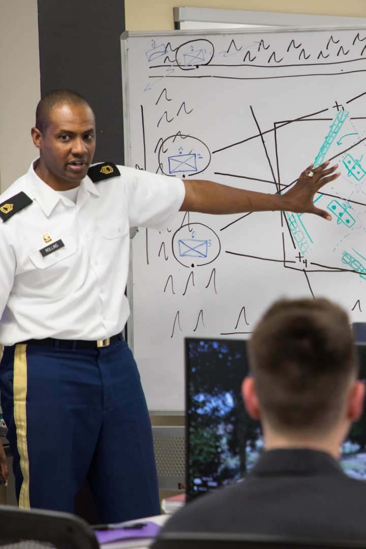 A cadet presents his capstone project to an audience of military and civilian partners.