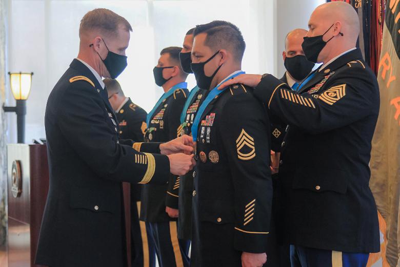 Commandant of Cadets Brig. Gen. Curtis A. Buzzard (left) places the Sgt. Audie  Murphy Medallion around the neck of recipient Brandon Roque (middle), a Department of Military Instruction instructor, during the Sgt. Audie Murphy Induction Ceremony March 29 in the Haig Room. 