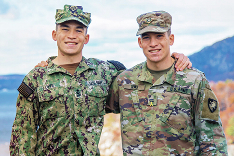 Class of 2023 Midshipman Jacob Lowe and Class of 2023 Cadet Josh Lowe embrace each other as they pose for a photo at Trophy Point with the view of the Hudson River in the background.    	       Photo courtesy of Dave Lowe