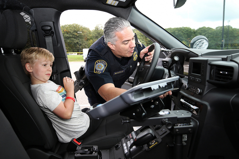 Ken Scott from the U.S. Mint Police shows 7-year-old Beau Bentley various items in his police car, to include how to work the siren. 