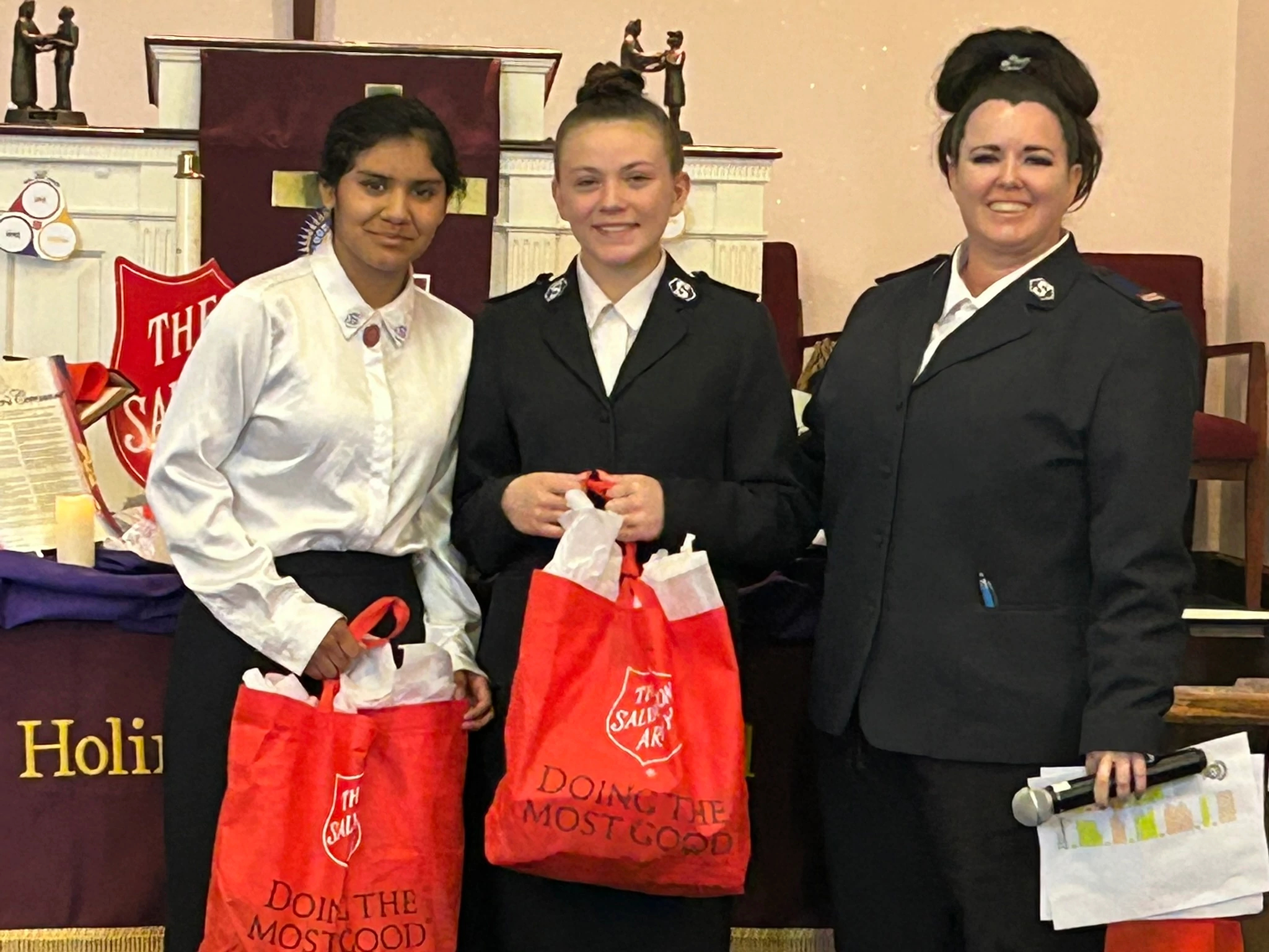 Young people in Salvation Army uniform holding red Salvation Army bags.