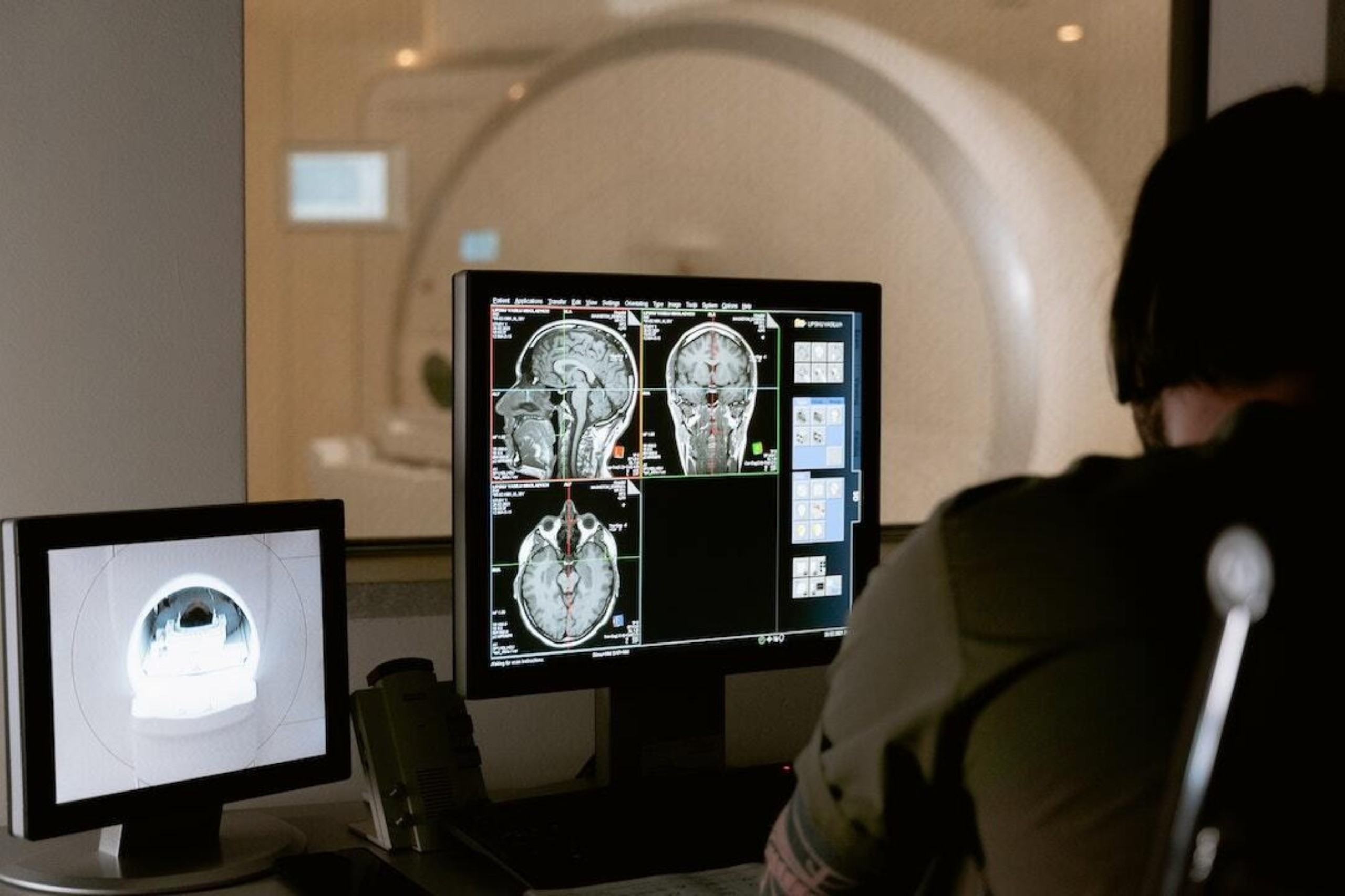 Image: A man looks at an MRI result on a computer in a dark room.