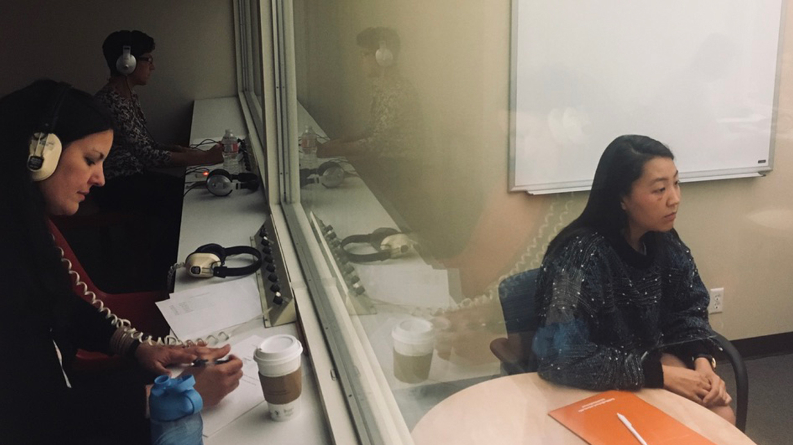 An Integrated Behavioral Health Scholars staff member conducting research takes notes while watching a study participant through a window.