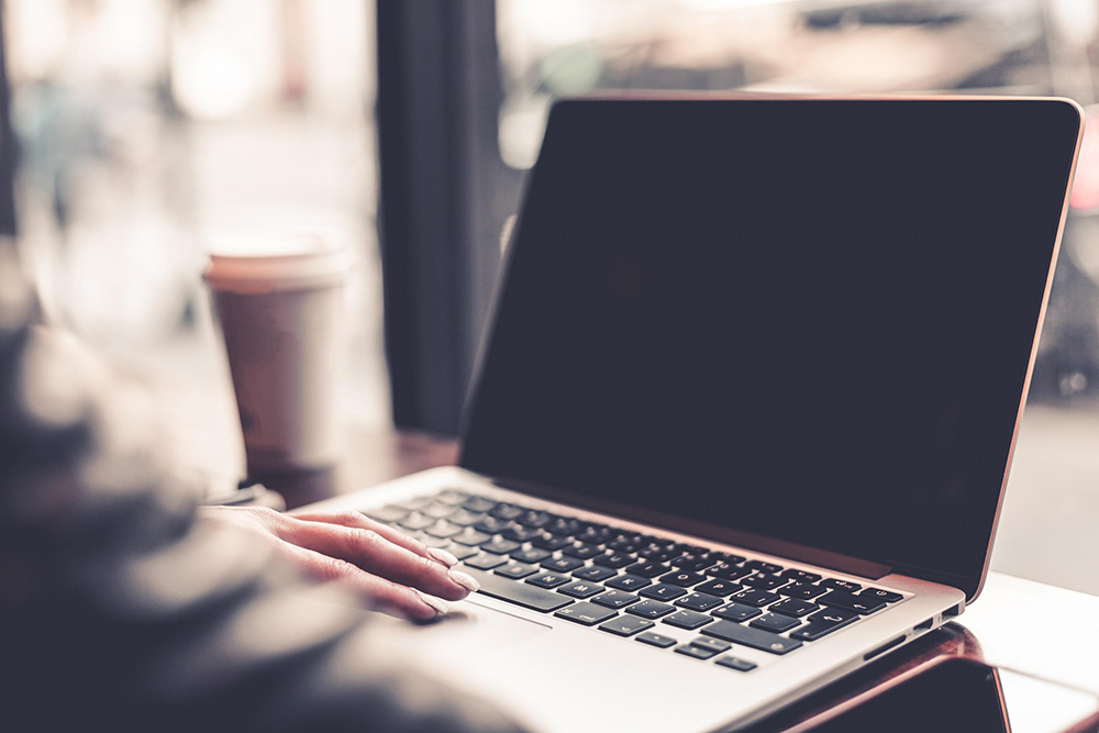 A student works on a laptop at a coffee shop.