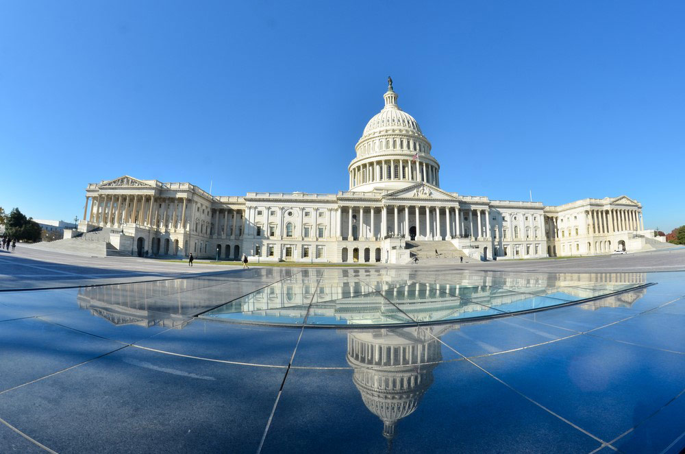 The U.S. capitol building and its reflection on the sidewalk.