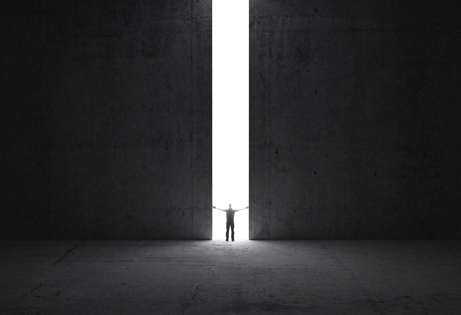 Silhouette of a person in the distance through a large crack of light in a wall