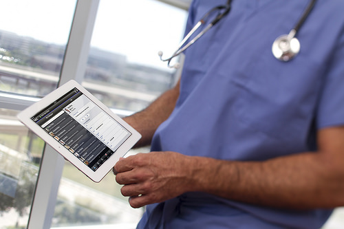 Healthcare professional looks at data on a silver tablet