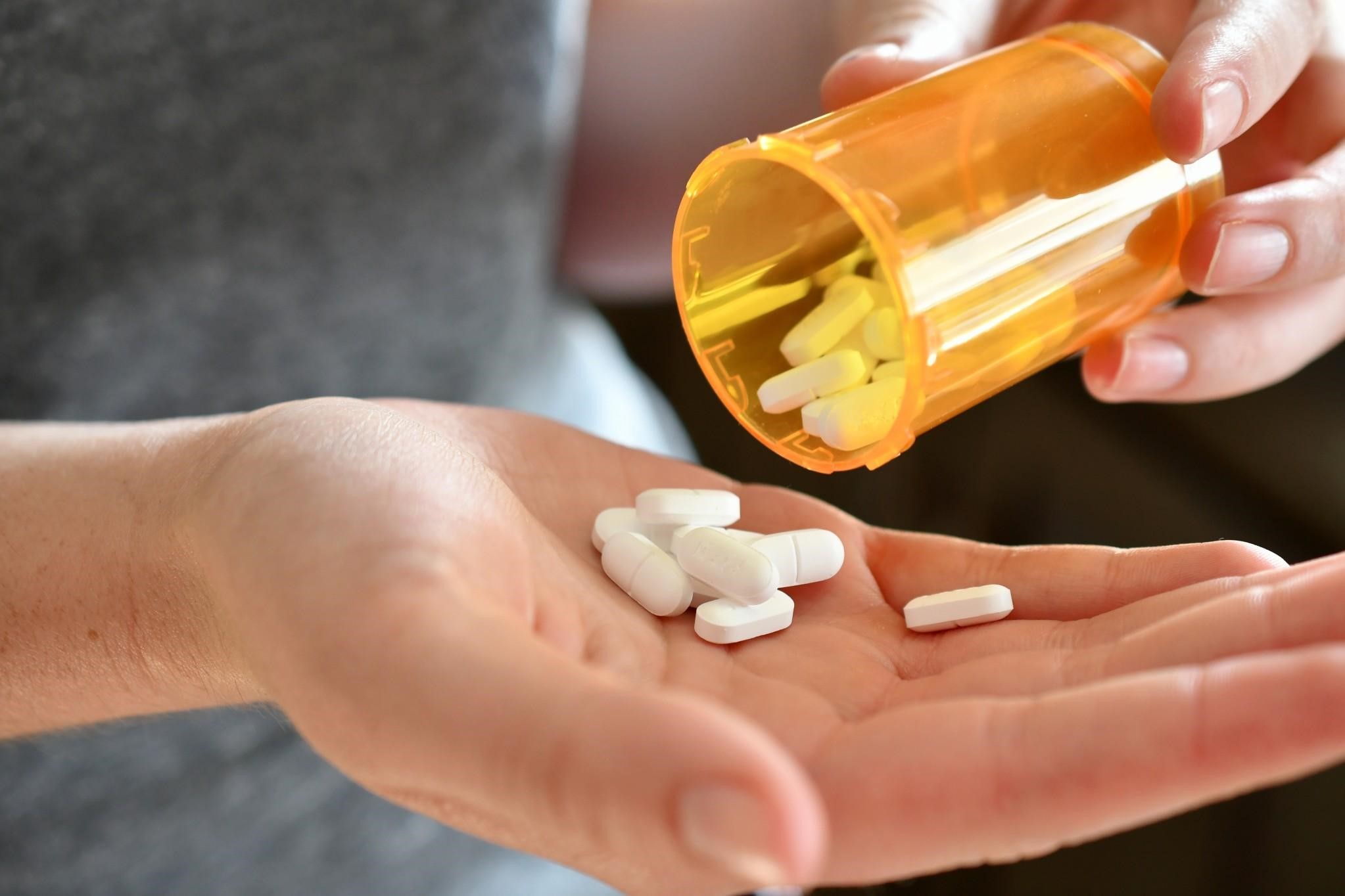 Person pouring out pills into their hand.