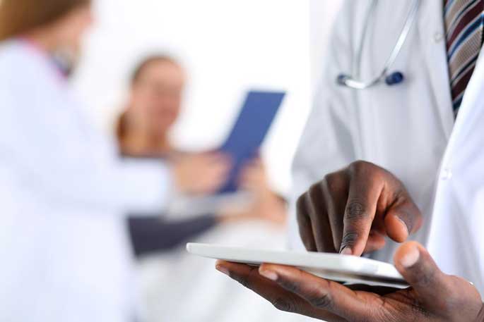 Three health professionals enter information on tablets