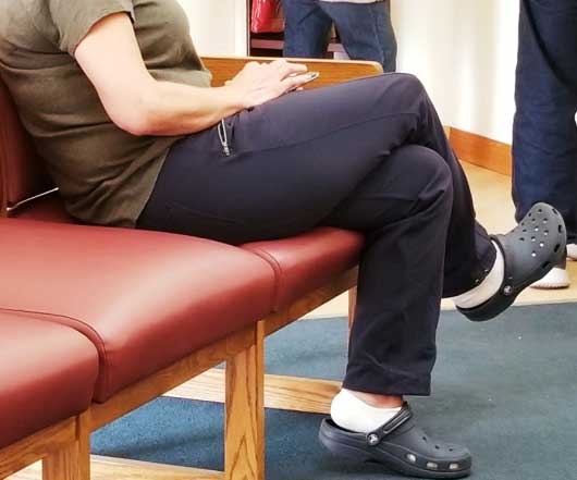 Patient in medical office waiting room uses smartphone
