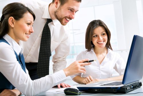  Young people in professional dress sitting near a laptop working together.