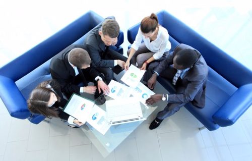Employees compare graphs during a project management meeting.