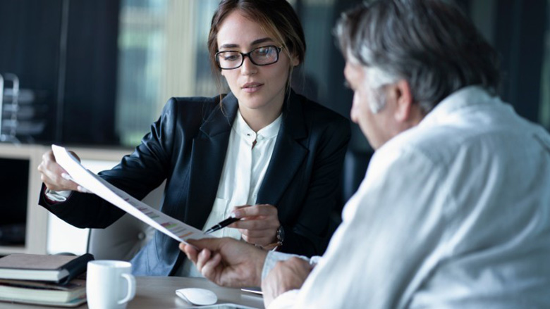 A business intelligence consultant reviews a report with a client.