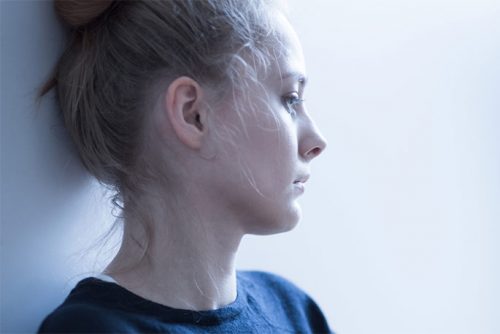 Woman with blond hair in a blue sweater looking into distance