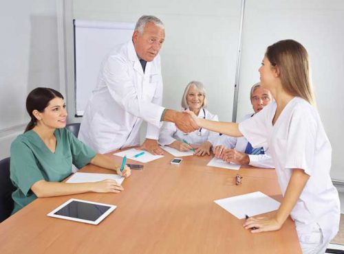 A group of nurse practitioners meet around a conference table.