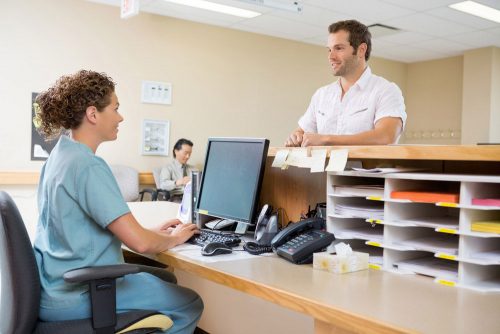 Male patient talking to the female nurse at the reception desk at hospital