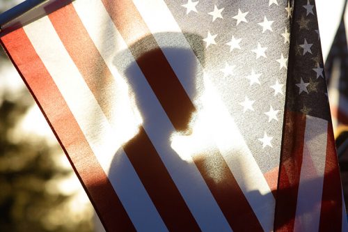 Silhouette of a soldier seen through the United States of America flag