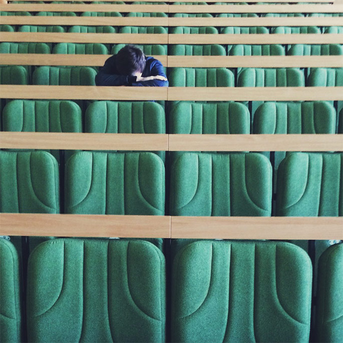 Student with head down in an empty classroom