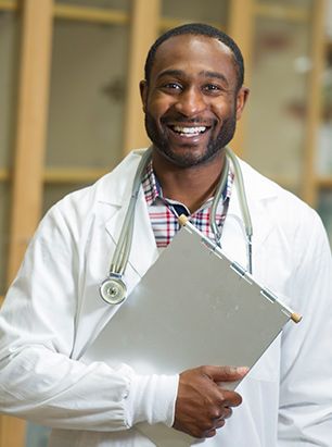 Male doctor smiling and holding clipboard