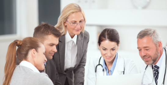 Nurse Administrator Talks to a Group of Doctors at the Office Desk