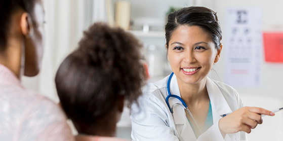 Female Nurse Practitioner With a Smiling Face Looking at a Child Patient 