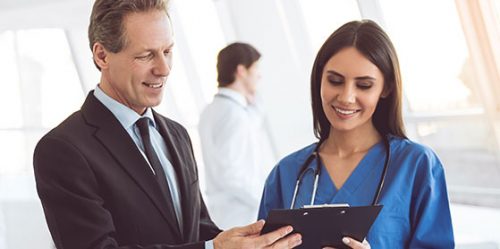 Older male in suit talks with younger nurse