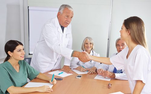 Older male doctor shakes hands with colleague
