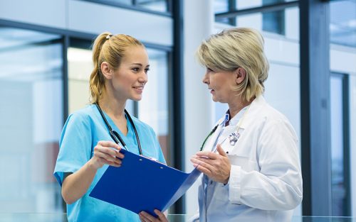 Doctor and nurse talking in hospital hallway