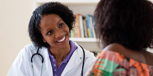 Female African American doctor consults with patient at her desk