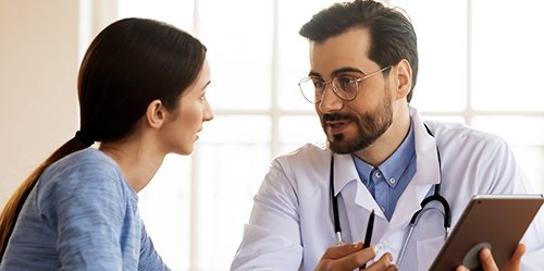 Younger male doctor consults with female patient