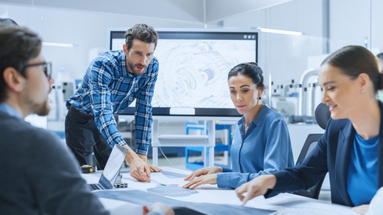 An engineering manager leads a team discussion around a conference table.