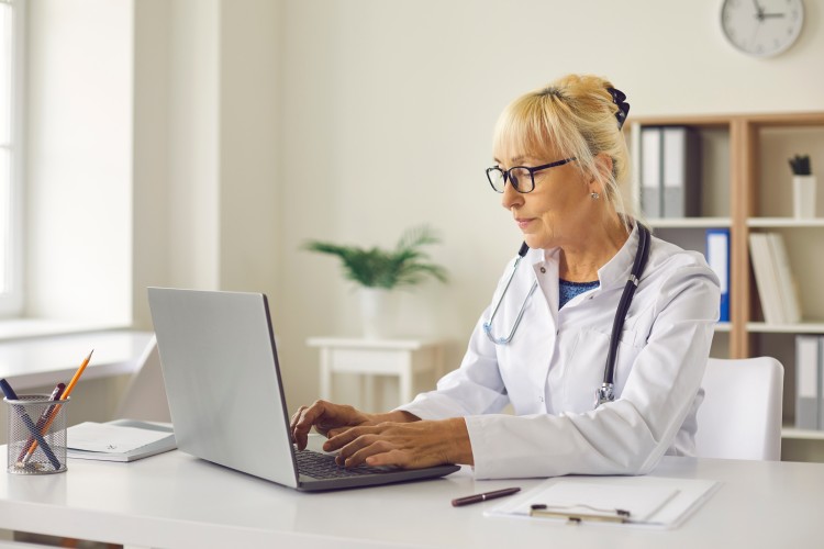 Director of nursing working at a desk with a computer in an office. 