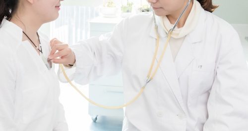 A nurse practitioner uses a stethoscope to listen to a patient’s heart.