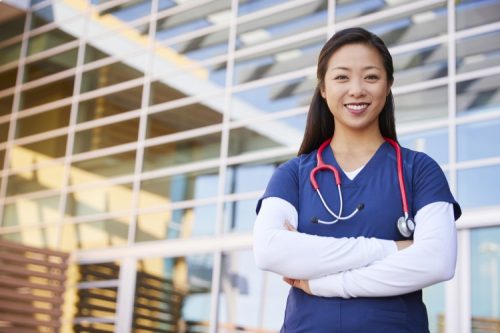 A nurse mentor stands in front of the hospital where she works.